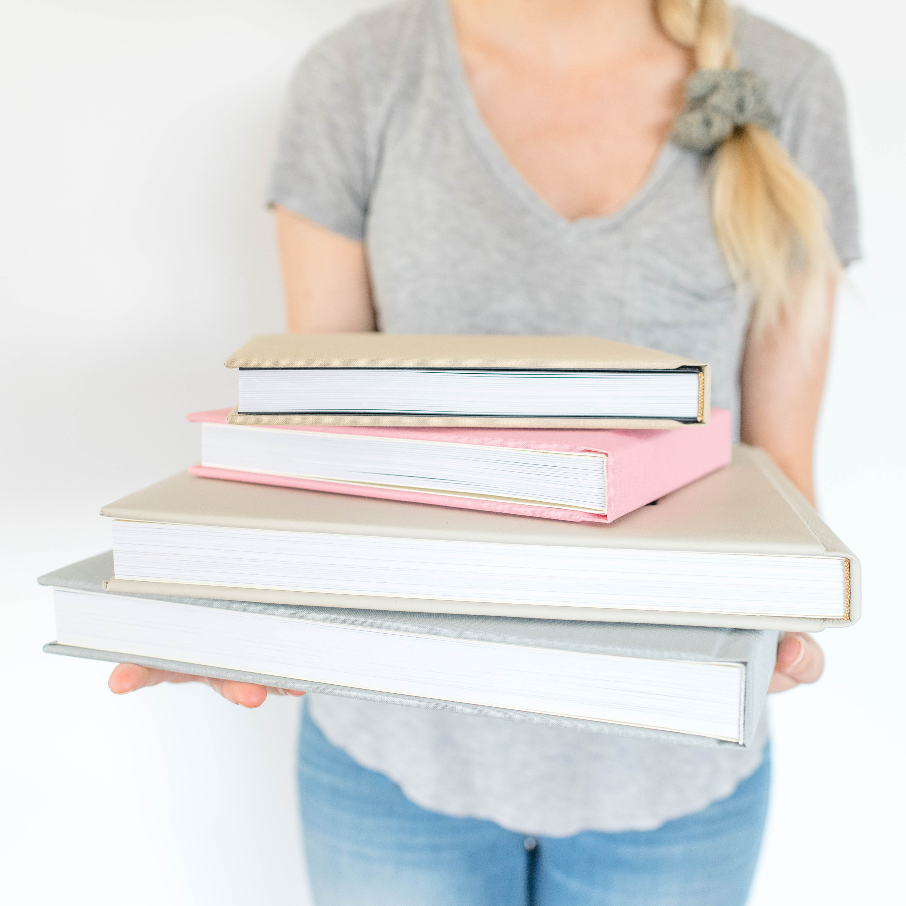 Women holding stack of high-end photo books